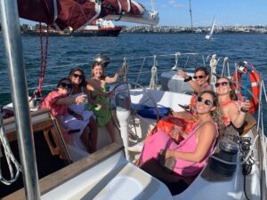 Cheers! Ladies enjoying the Bachelorette Cruise, seated at the aft of the sailboat on a beautiful sunny day.